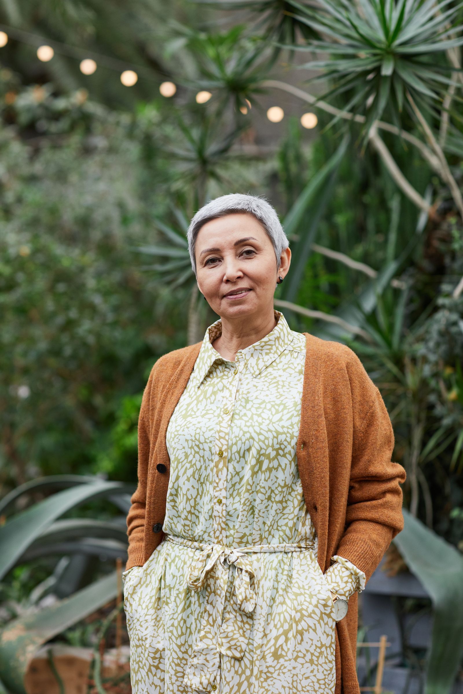 Portrait of an elegant senior woman smiling in a lush garden setting.